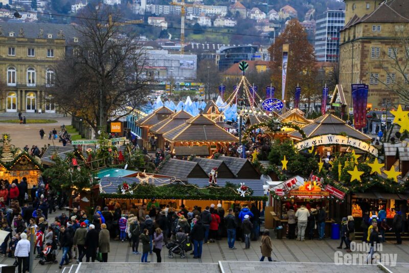 Overview of a German Christmas Market with many people and a German city in the background