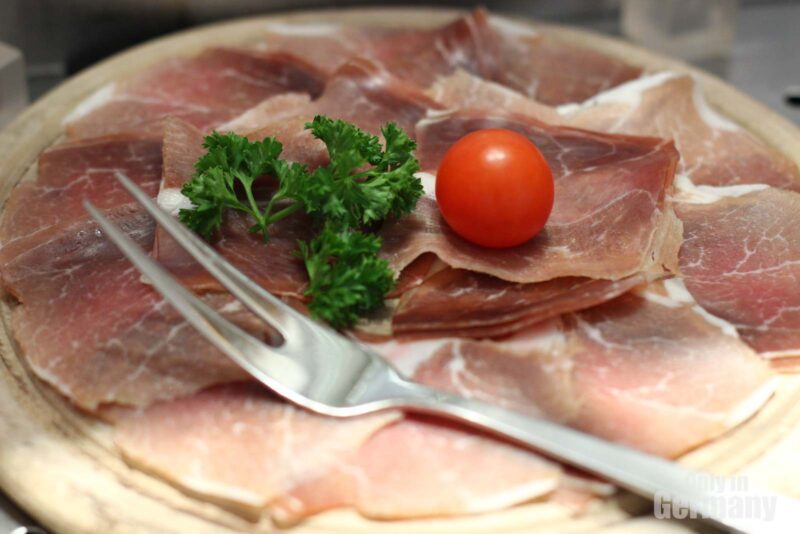 Close up of cold cuts on a plate with a cherry tomato and a fork as part of a breakfast in Germany 